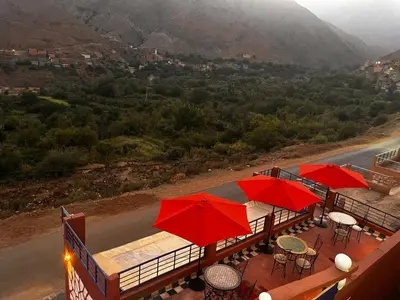 a deck with red umbrellas and tables with a view at Auberge Touristique Toubkal in Imlil