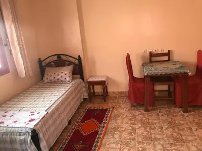 a bedroom with two beds and a table and chairs at Auberge Touristique Toubkal in Imlil