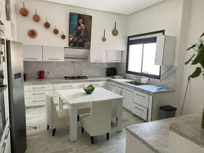 a white kitchen with a white table and chairs at dar Jellouna Zaraba in Oulad Akkou