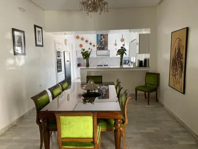 a dining room with a table and green chairs at dar Jellouna Zaraba in Oulad Akkou