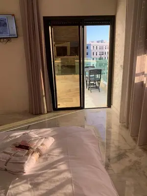 a bed in a room with a view of a patio at Luxueux - Vue sublime - Fes City Center - à 2 min du parc de champs de course in Fès