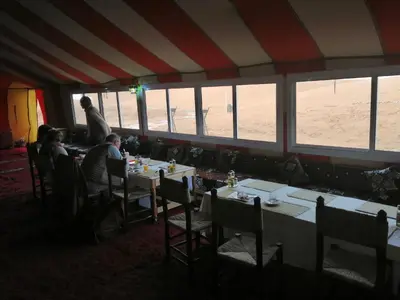 a restaurant with people sitting at tables in a room with a beach at Bivouac Luxe Masandoia Meteorites in Lac Yasmins