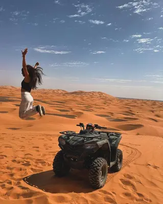 a woman running in the desert with a wheeler at Honeymoon Luxury Camp in Merzouga