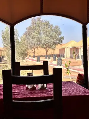 a view through a window of a table and a field at Honeymoon Luxury Camp in Merzouga
