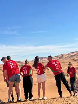 a group of people standing in the desert at Honeymoon Luxury Camp in Merzouga
