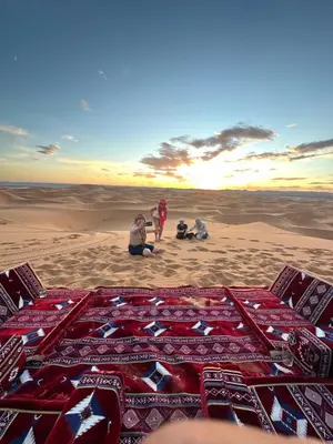 a group of people sitting on the sand in the desert at Honeymoon Luxury Camp in Merzouga