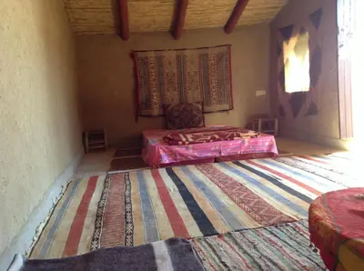 a bedroom with a bed and a rug on the floor at Secret du Sahara in Merzouga