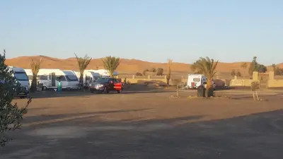 a group of vehicles parked in a parking lot in the desert at Secret du Sahara in Merzouga