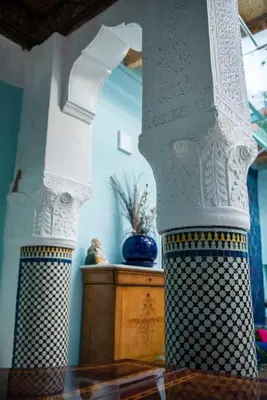 two white columns in a room with a wooden table at dar annee in Fès