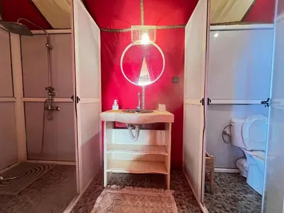 a bathroom with a sink and a mirror and a toilet at Sindibad Desert Camp in Merzouga