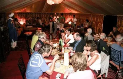 a group of people sitting at a table eating at Sindibad Desert Camp in Merzouga