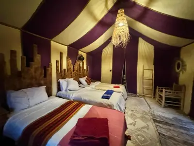 two beds in a room with purple and white walls at Sindibad Desert Camp in Merzouga