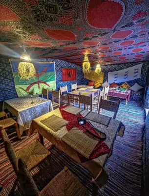 a dining room with tables and chairs and a colorful ceiling at Sindibad Desert Camp in Merzouga