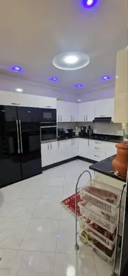 a large kitchen with white cabinets and a cart in it at Galaxy appartement MEKNES in Meknès