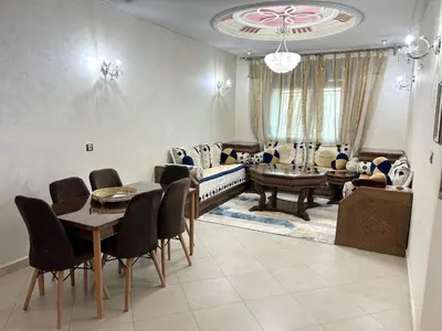 a living room with a table and a couch at Grand appartement familial - Calme & bien situé à Mèknes in Meknès