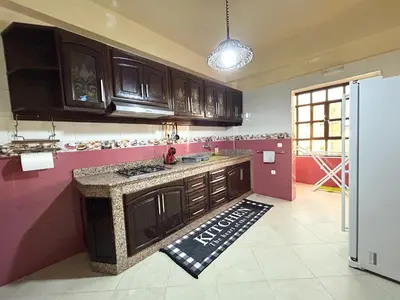 a kitchen with brown cabinets and a counter top at Grand appartement familial - Calme & bien situé à Mèknes in Meknès