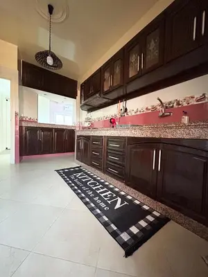 a kitchen with wooden cabinets and a rug on the floor at Grand appartement familial - Calme & bien situé à Mèknes in Meknès