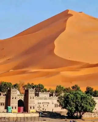 a building in front of a sand dune at Merzouga Hous in Merzouga