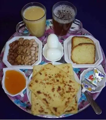 a plate of food with eggs and bread and drinks at Merzouga Hous in Merzouga