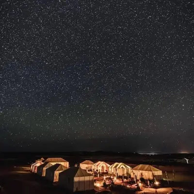 a row of tents under a starry sky at night at Merzouga Hous in Merzouga