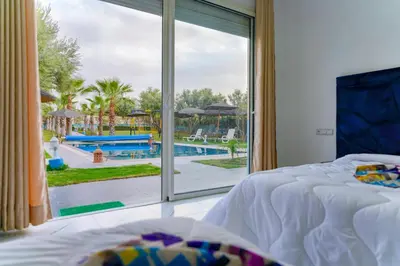 a bedroom with a large window looking out onto a pool at Villa de Luxe à Marrakech avec Piscine Chauffée Privée in Aghmat