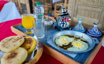 a table with a plate of eggs and bread and drinks at Villa de Luxe à Marrakech avec Piscine Chauffée Privée in Aghmat