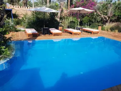 a large swimming pool with lounge chairs and an umbrella at Villa palmeraie Marrakech in Najem