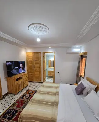 a bedroom with a large bed and a television at Riad Gogo in Aït Ben Haddou