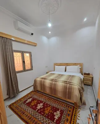a bedroom with a large bed and a rug at Riad Gogo in Aït Ben Haddou