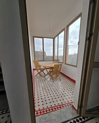 a table and chairs in a room with windows at Riad Gogo in Aït Ben Haddou