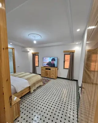 a bedroom with a bed and a flat screen tv at Riad Gogo in Aït Ben Haddou