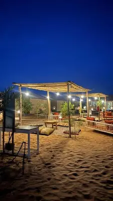 a pavilion on the beach at night with lights at Desert luxury in Hassilabied
