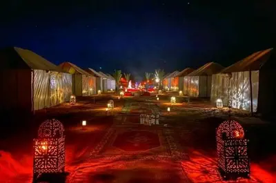 a parking lot with lit up huts at night at Desert luxury in Merzouga