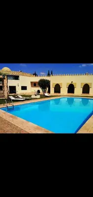 a large blue swimming pool in front of a building at Villa athis in Fourou