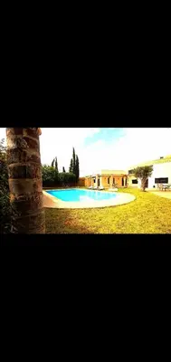 a small swimming pool in a field with a building at Villa athis in Fourou
