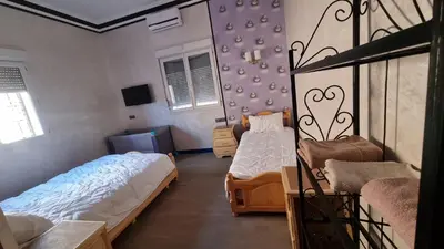 a bedroom with two beds and a bed and a window at Villa kaddi in Tinerhir