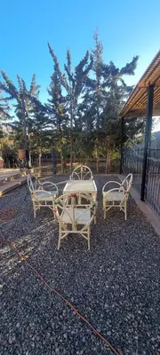 three chairs and a table in a gravel yard at Villa kaddi in Tinerhir
