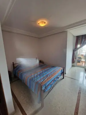 a bedroom with a bed in the corner of a room at Ilar Appartement in Oulad Akkou