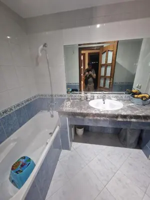 a man taking a picture of a bathroom with a tub and sink at Ilar Appartement in Oulad Akkou