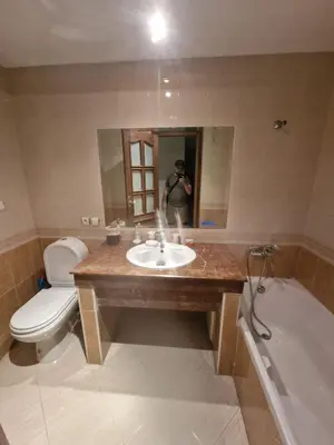 a man taking a picture of a bathroom with a sink and tub at Ilar Appartement in Oulad Akkou