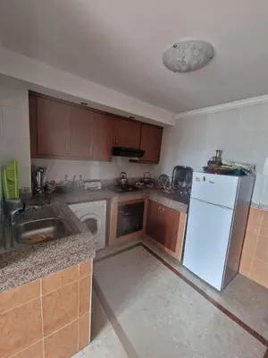 a kitchen with a white refrigerator and a dishwasher at Ilar Appartement in Oulad Akkou