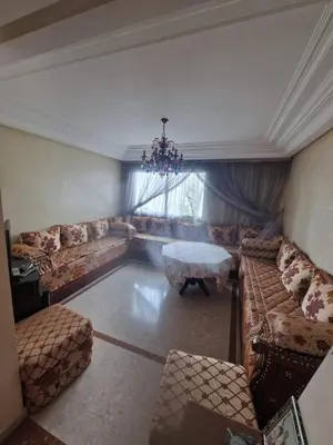 a living room with couches and a table and a chandelier at Ilar Appartement in Oulad Akkou