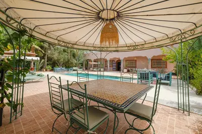 a table and chairs under an umbrella next to a pool at Dar Salah - Eddine Oasis Pool & SPA in Marrakech