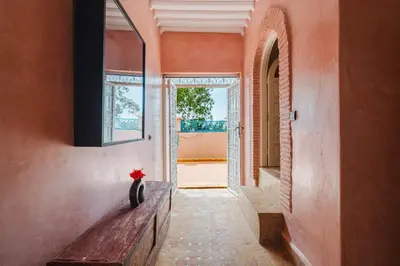 a hallway with a bench and a vase with a red flower at Dar Salah - Eddine Oasis Pool & SPA in Marrakech