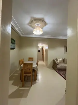 a dining room with a table and chairs and a couch at Grand appartement de 3 chambres Idéal familles et groupes Résidence sécurisée in Marrakech