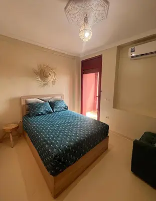 a bedroom with a bed with blue sheets and a window at Grand appartement de 3 chambres Idéal familles et groupes Résidence sécurisée in Marrakech