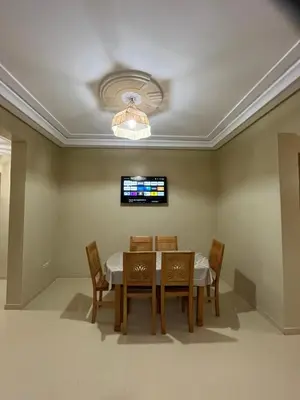 a dining room with a table and chairs and a tv at Grand appartement de 3 chambres Idéal familles et groupes Résidence sécurisée in Marrakech