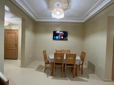 a dining room with a table and chairs and a tv at Grand appartement de 3 chambres Idéal familles et groupes Résidence sécurisée in Marrakech