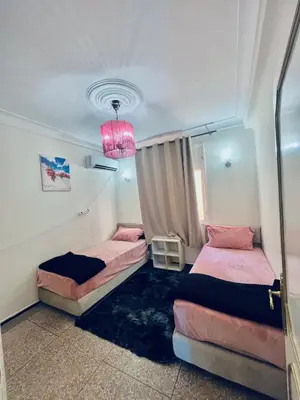 a bedroom with two beds and a pink lamp at Appartement luxe 2 Chambres 5 min du Centre Ville in Fès