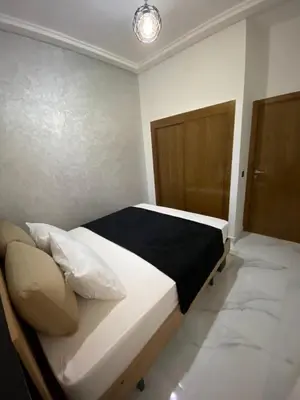 a bedroom with a bed with a black and white comforter at Appartement lux résidence fermée sécurisé parking gratuit in Fès